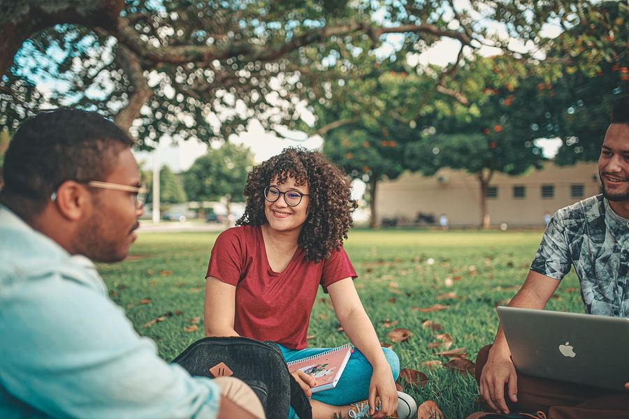 College students talking together on a campus lawn.